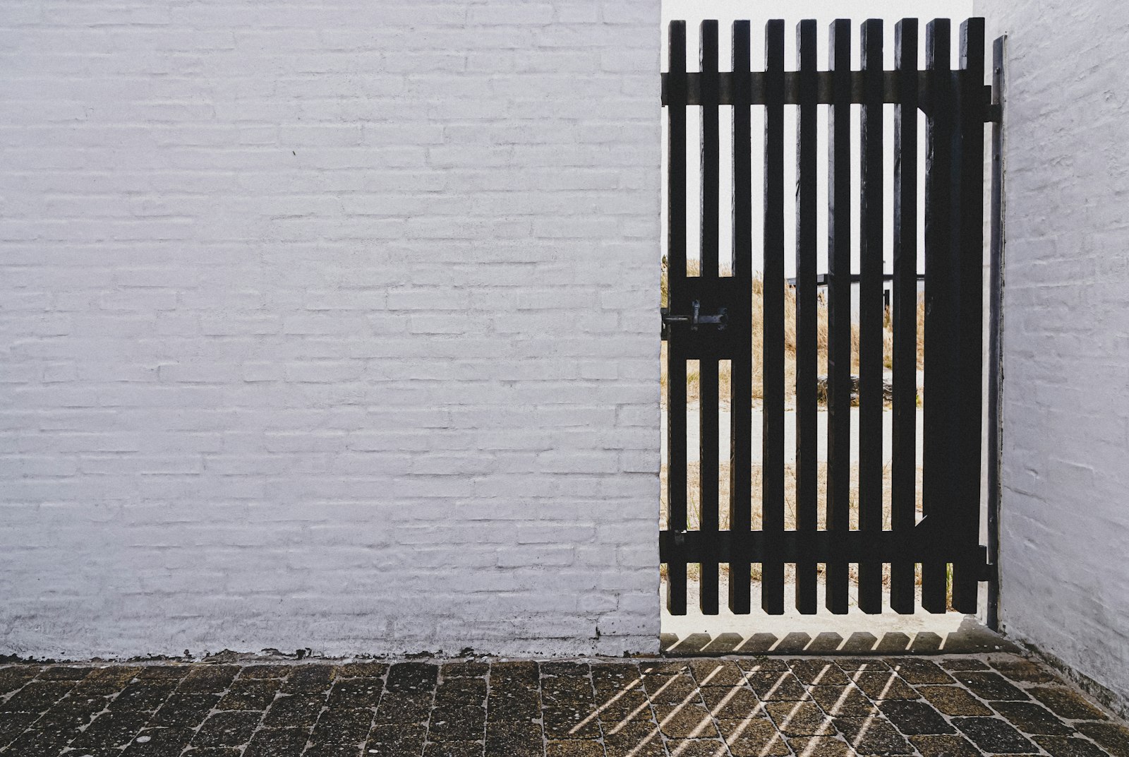 Portão pedonal metálico lacado a preto em muro branco